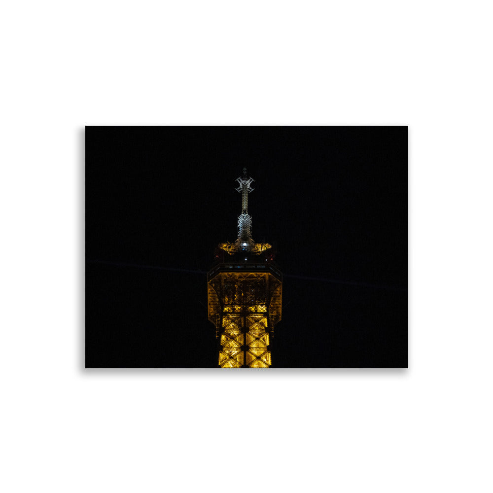 Photographie 'L'antenne' de la partie supérieure de la Tour Eiffel illuminée de nuit.