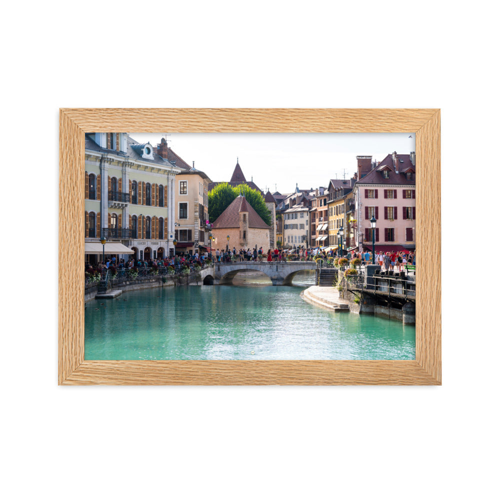 Vue estivale d'Annecy, mettant en lumière le Pont Perrière et le Palais de l'Île, encadrée d'un bois de chêne.