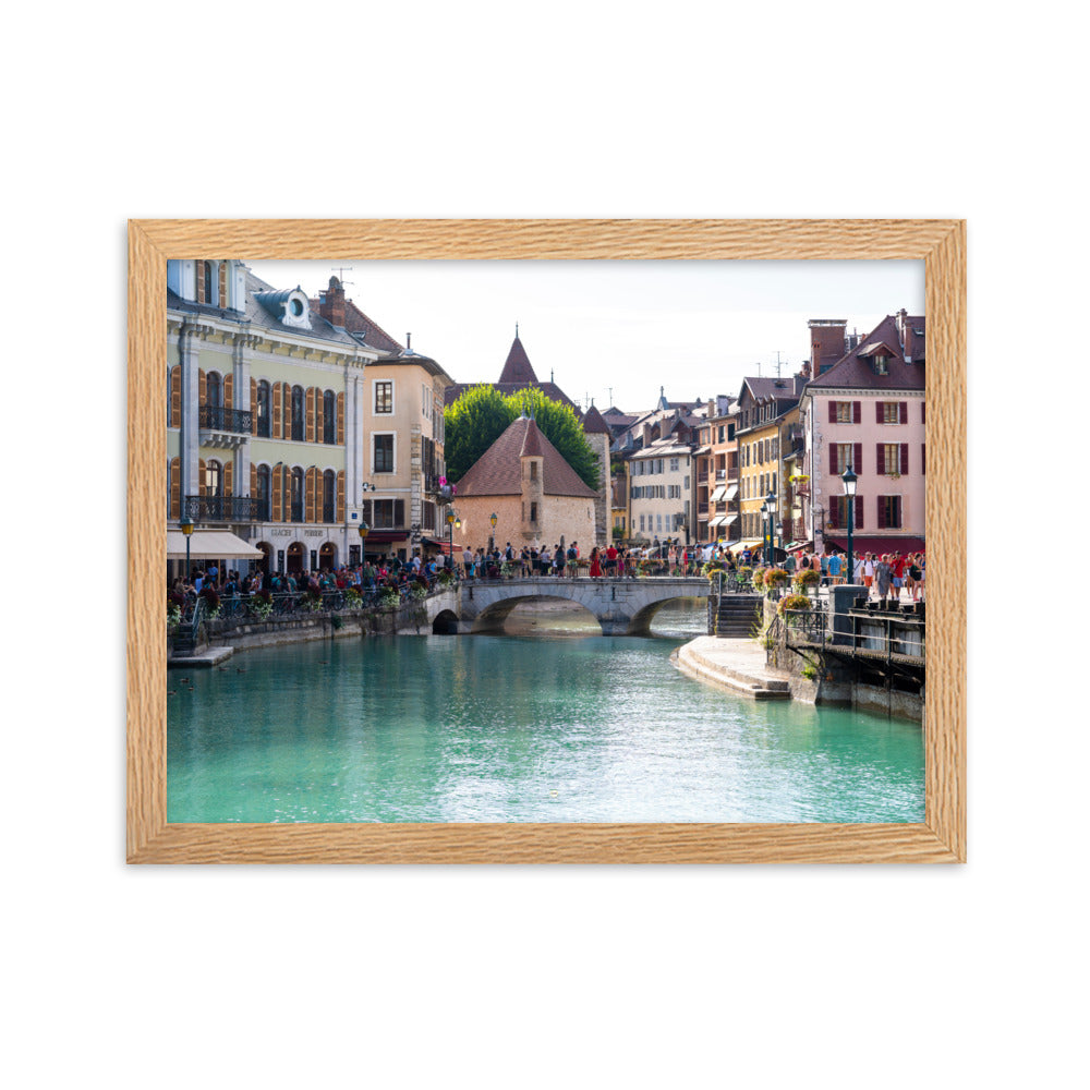 Vue estivale d'Annecy, mettant en lumière le Pont Perrière et le Palais de l'Île, encadrée d'un bois de chêne.