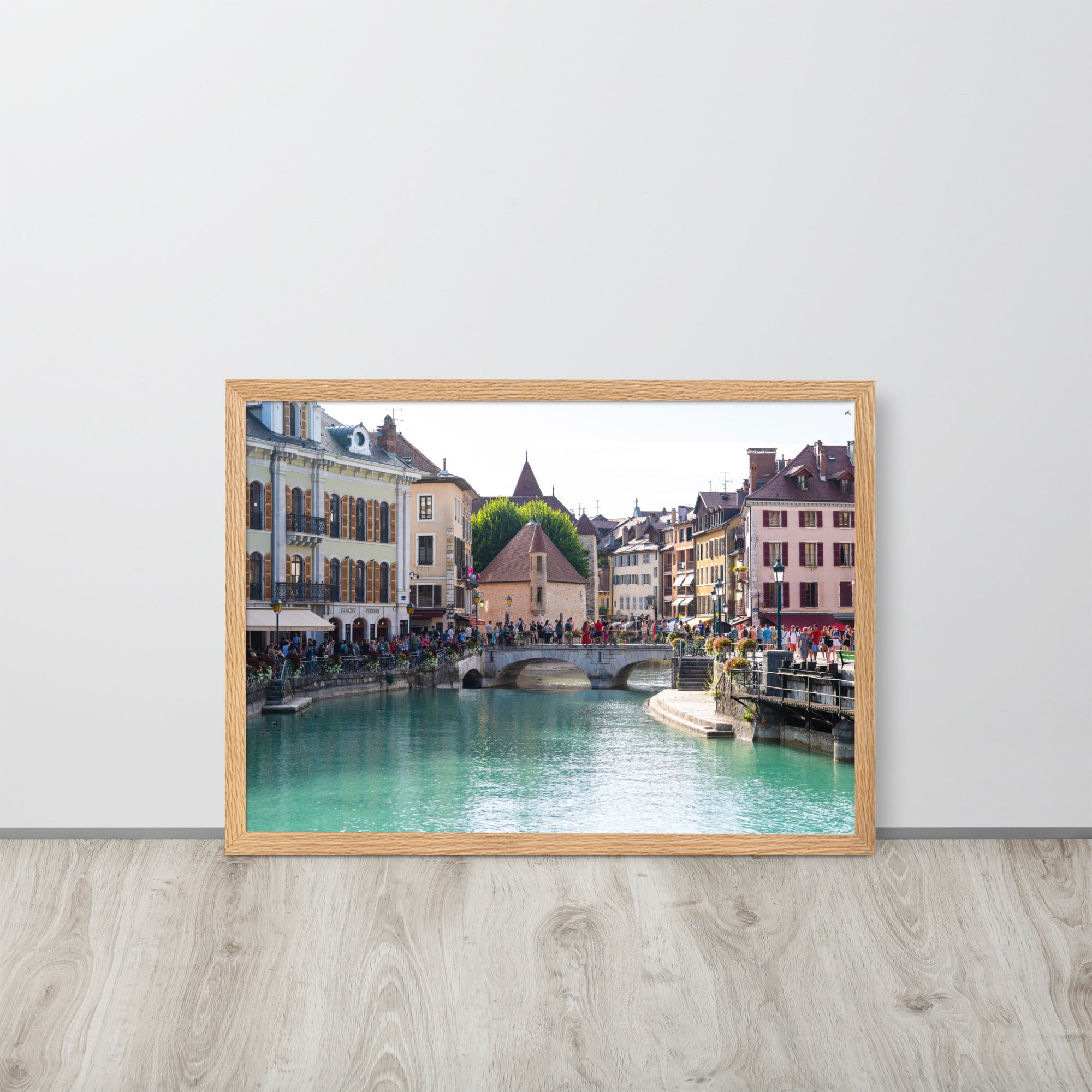 Vue estivale d'Annecy, mettant en lumière le Pont Perrière et le Palais de l'Île, encadrée d'un bois de chêne.
