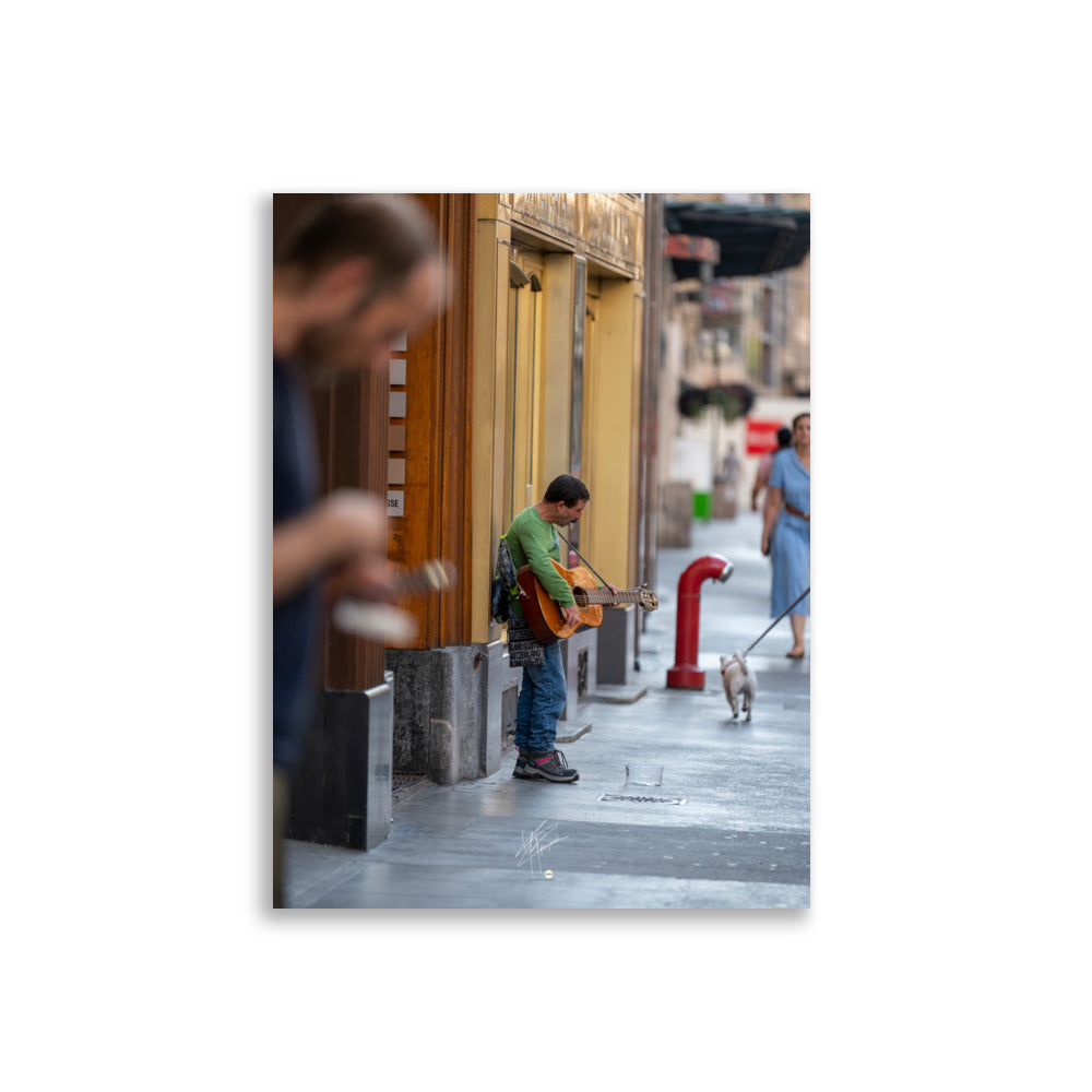 Poster photographique 'Le Petit Guitariste', une image d'un homme jouant de la guitare acoustique dans les rues de Genève, symbolisant la passion et la créativité de la musique de rue.