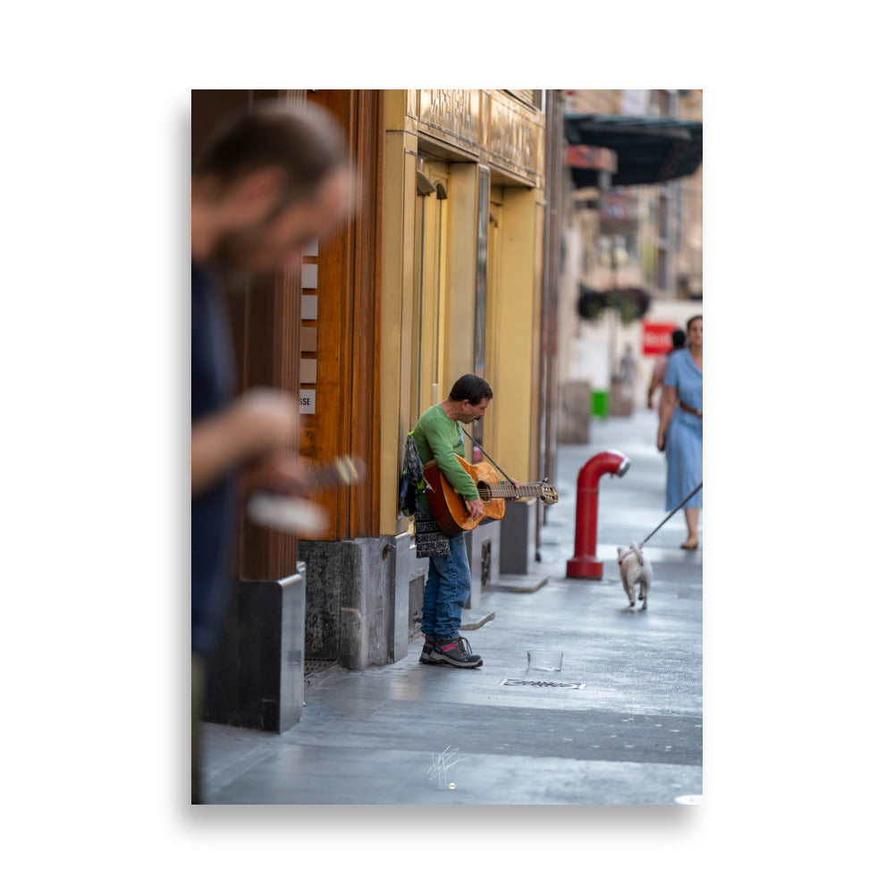 Poster photographique 'Le Petit Guitariste', une image d'un homme jouant de la guitare acoustique dans les rues de Genève, symbolisant la passion et la créativité de la musique de rue.