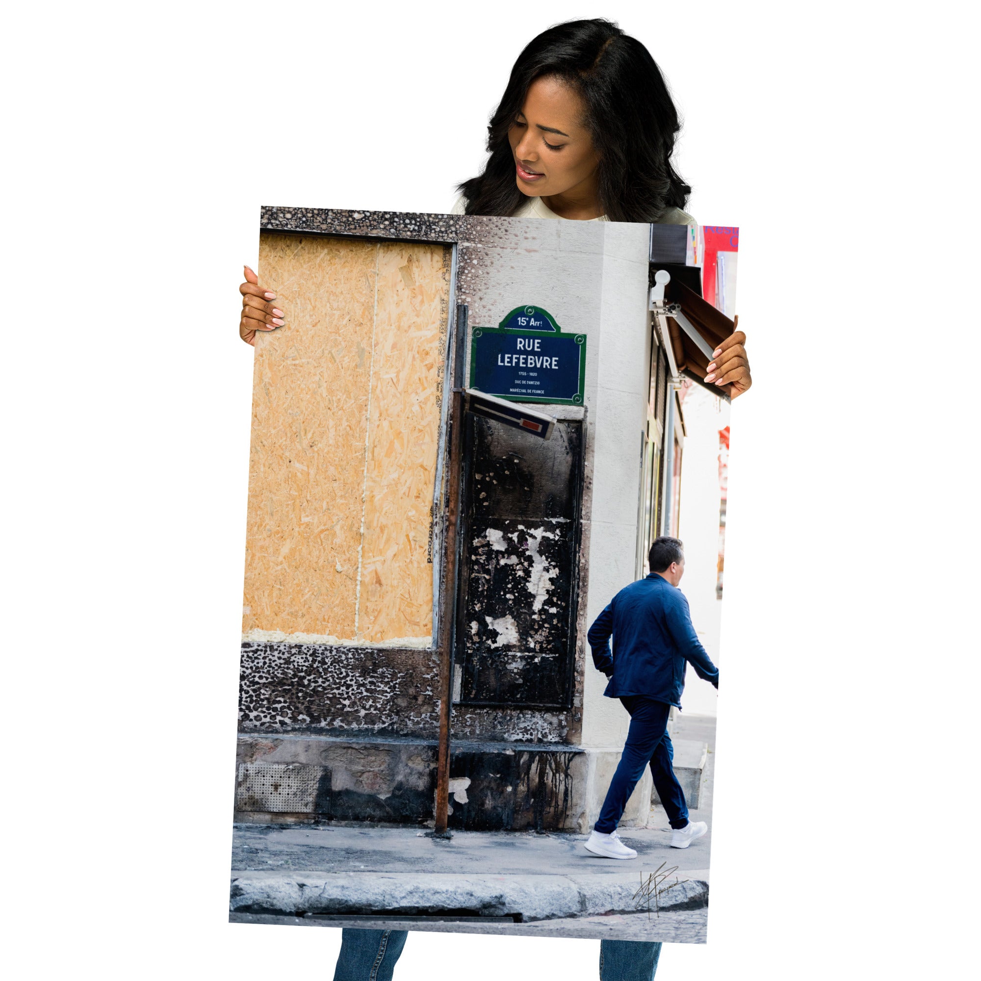 Photographie de la "Rue Lefebvre" après un incendie, montrant des traces de suie, un panneau de sens interdit plié et un passant.