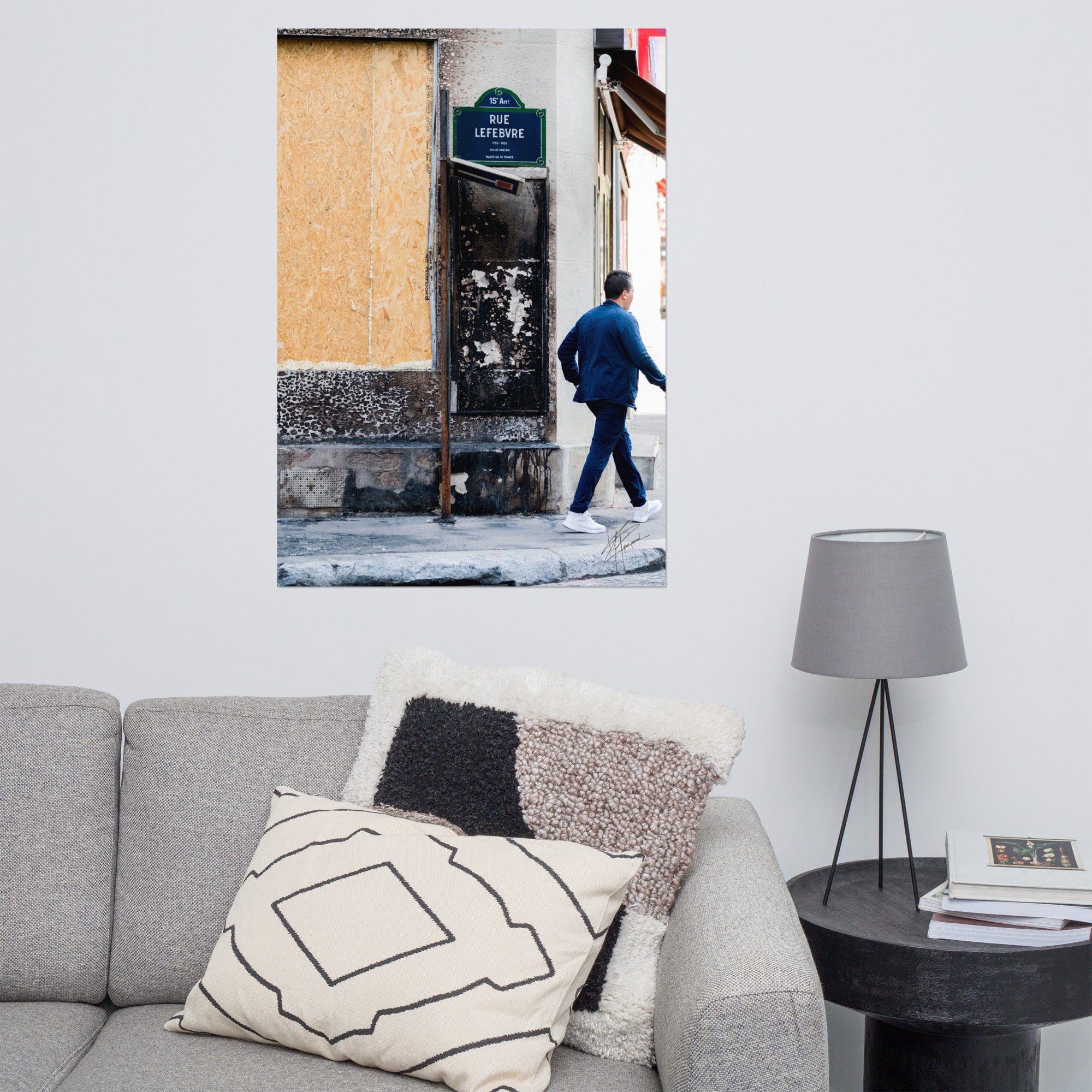 Photographie de la "Rue Lefebvre" après un incendie, montrant des traces de suie, un panneau de sens interdit plié et un passant.