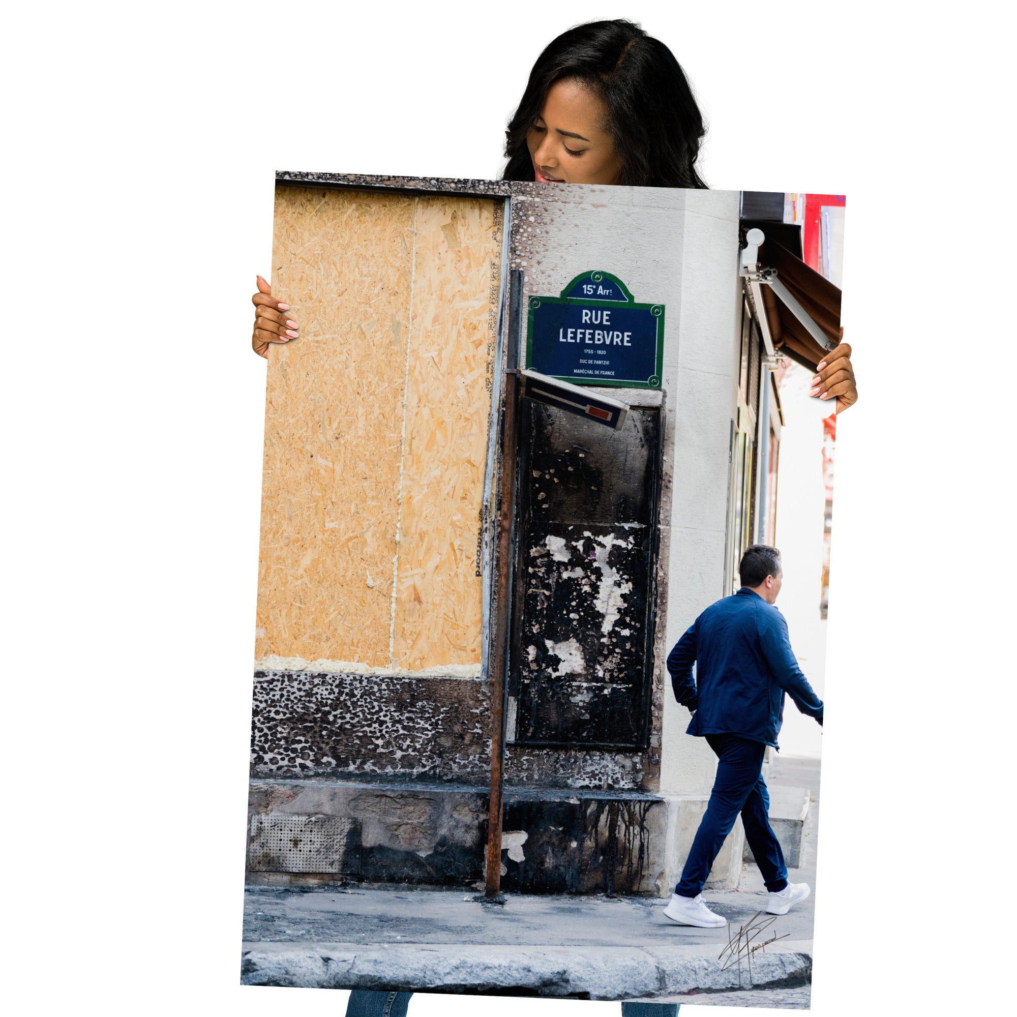 Photographie de la "Rue Lefebvre" après un incendie, montrant des traces de suie, un panneau de sens interdit plié et un passant.