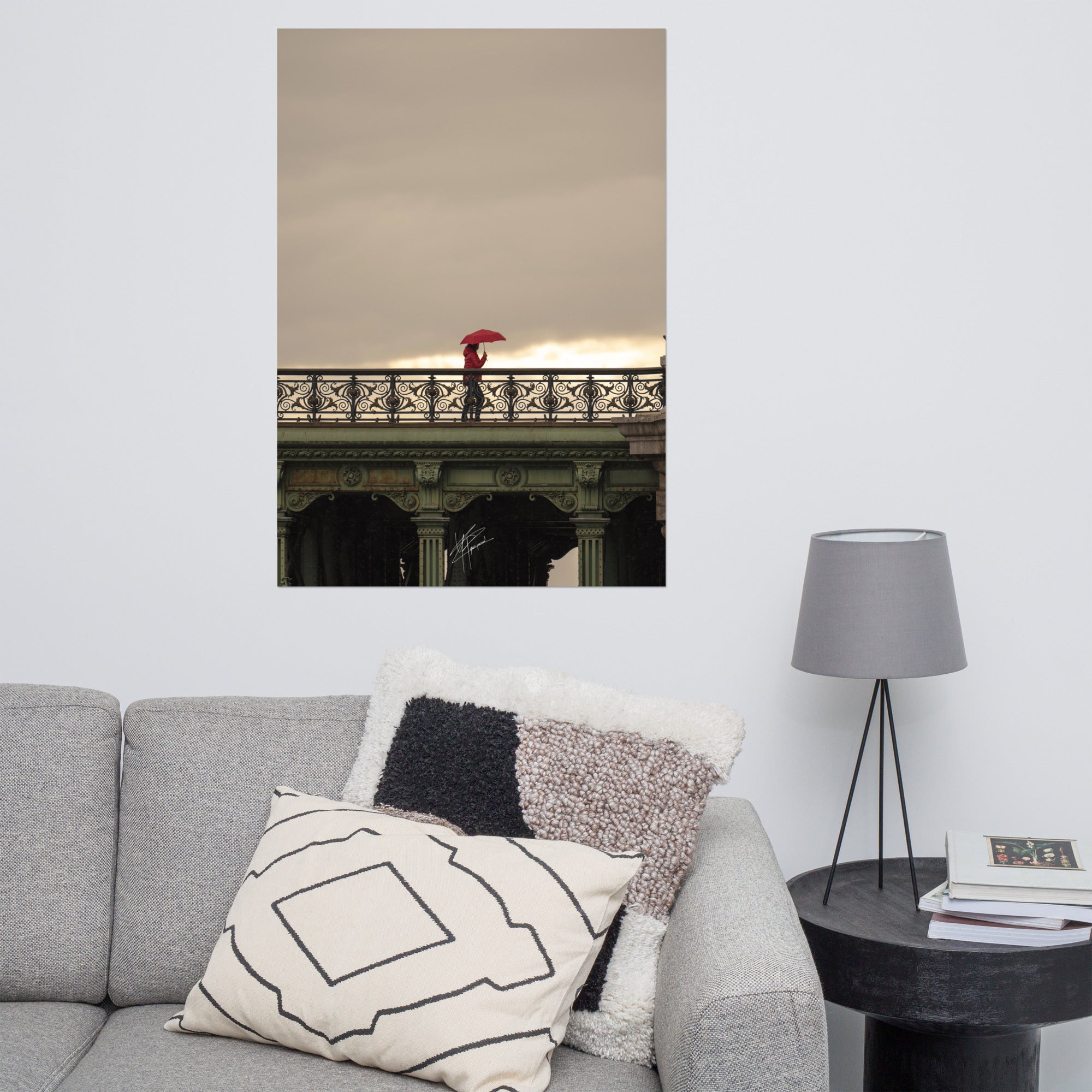 Photographie d'une femme traversant un pont parisien avec un parapluie rouge vif sur fond de paysage pluvieux.