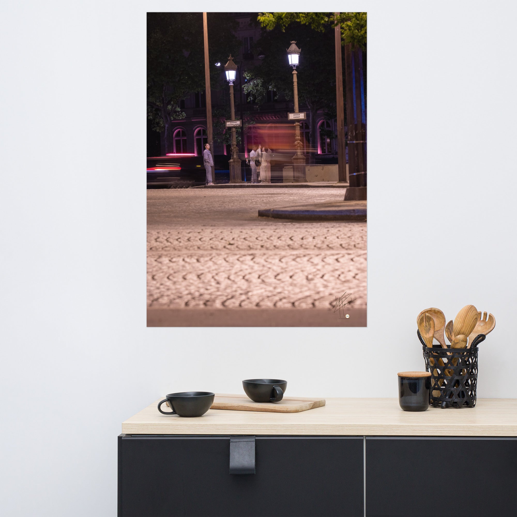 Photographie nocturne de l'Avenue de la Grande Armée à Paris, montrant quatre touristes prenant une photo, avec un arrière-plan de voitures en mouvement grâce à une longue exposition.