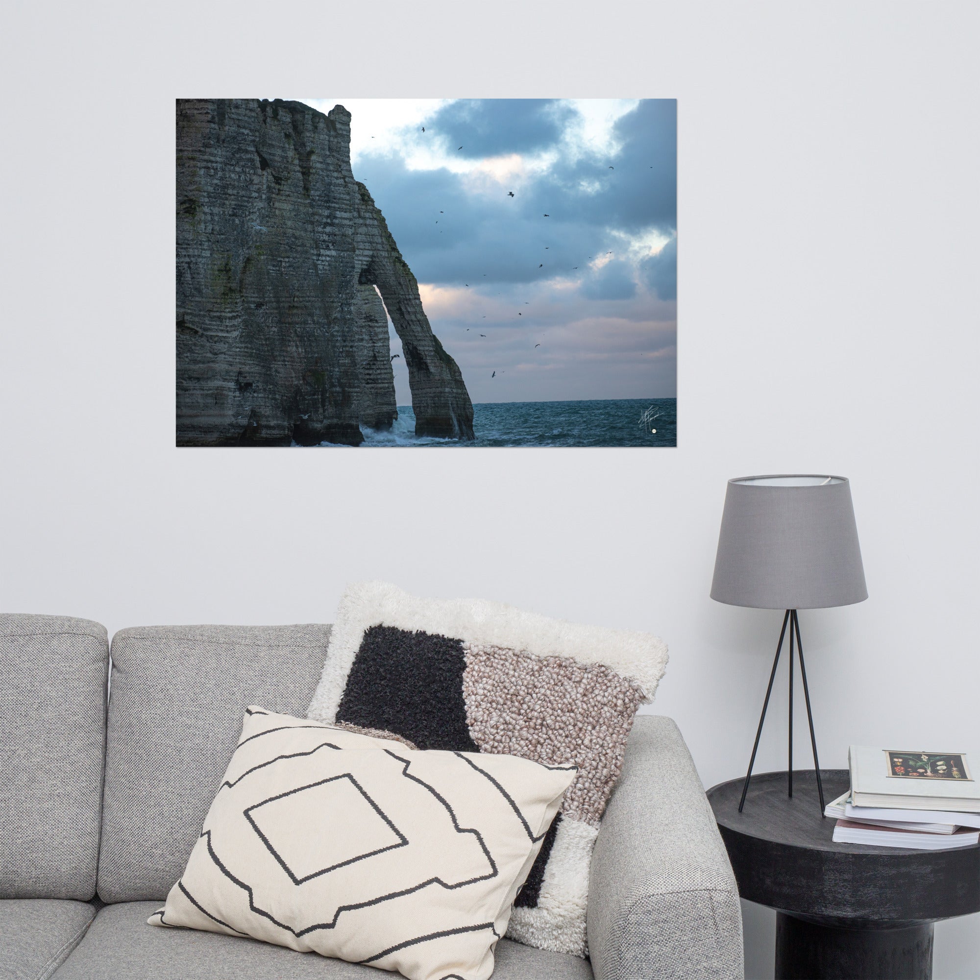 Vue panoramique des falaises d'Étretat avec des vagues s'écrasant puissamment sur la côte, sous un ciel nuageux où les mouettes virevoltent, incarnant la beauté sauvage de la Normandie.