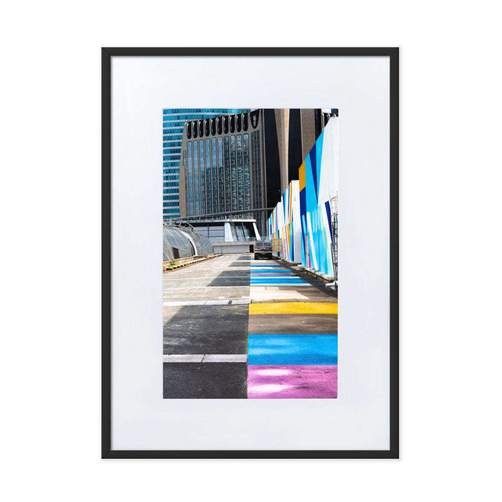 Poster encadré 'Palette' représentant une rue vibrante de couleurs contrastant avec des structures architecturales modernes, incarnant un mélange d'urbanisme et d'art.