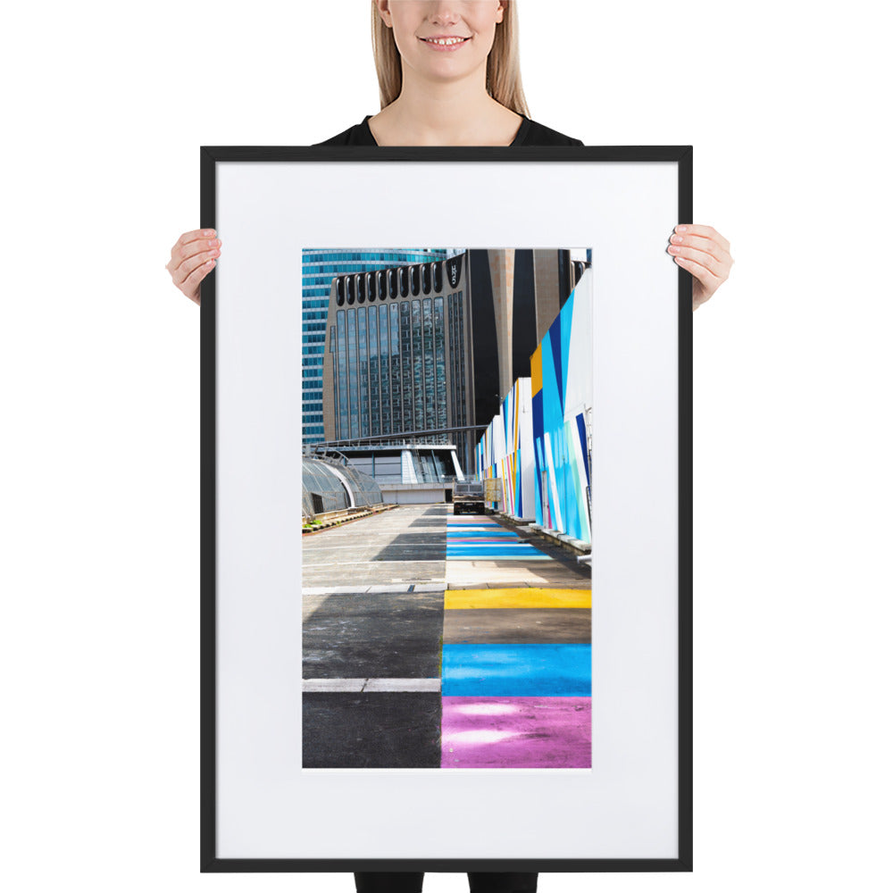 Poster encadré 'Palette' représentant une rue vibrante de couleurs contrastant avec des structures architecturales modernes, incarnant un mélange d'urbanisme et d'art.