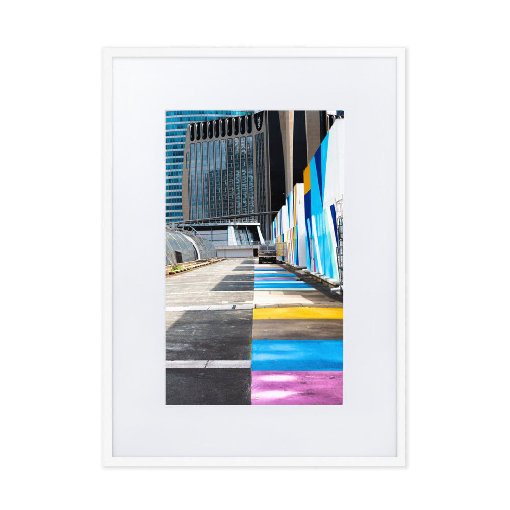 Poster encadré 'Palette' représentant une rue vibrante de couleurs contrastant avec des structures architecturales modernes, incarnant un mélange d'urbanisme et d'art.
