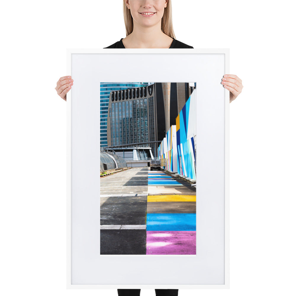 Poster encadré 'Palette' représentant une rue vibrante de couleurs contrastant avec des structures architecturales modernes, incarnant un mélange d'urbanisme et d'art.
